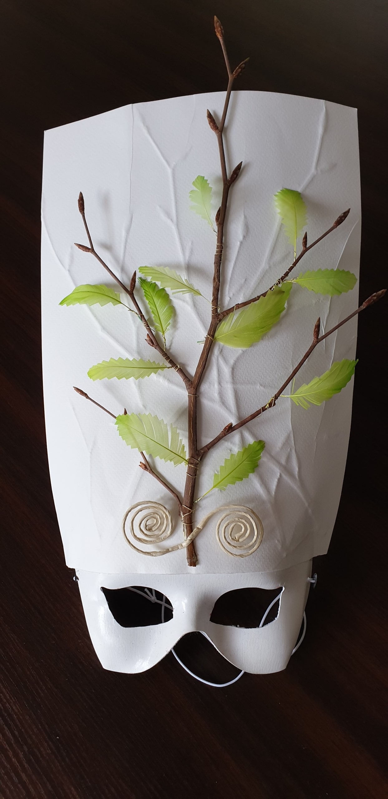 Photo du masque de Catherine, fait de branches et de plumes vertes en formes de feuilles